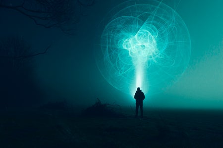 A man looks up at a mysterious swirl of lights in the night sky.