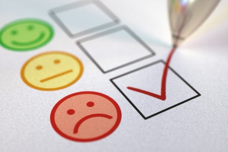 Pen making check mark on negative, frowny face feedback option on survey