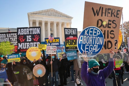 Demonstrators holding signs gather in front of the U.S. Supreme Court.