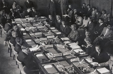 Eastern and Western nuclear scientists are shown sitting around a large conference table at the closing session of their two month meeting in Geneva, Switzerland on August 22, 1958