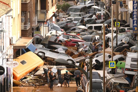 Cars are piled in the street with other debris.