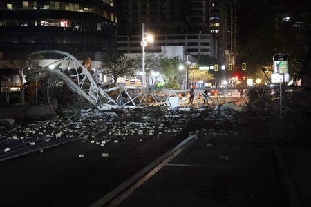 Crane sits on the street after crashing down into the building.