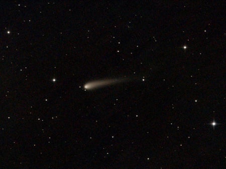 Comet with trail seen in night sky with stars