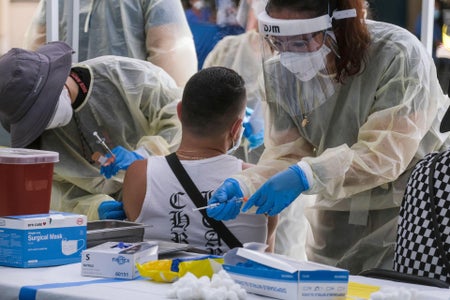 Rear view of person receiving vaccine at public park