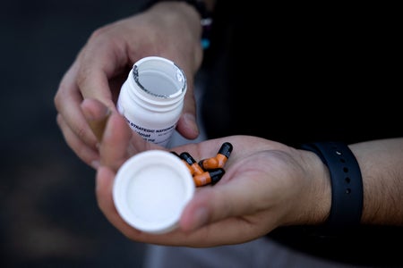 Hand holding pills and prescription pill bottle