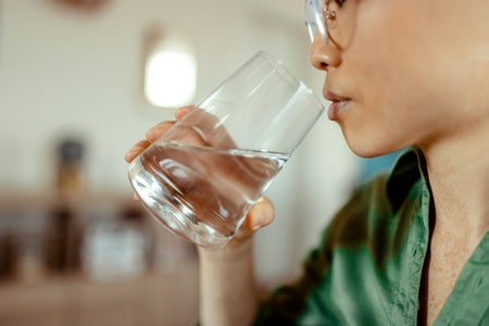 Model holding glass of water up to their mouth to drink