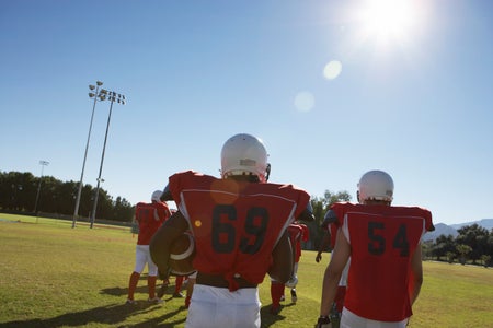 Football players with red top and numbers 69 and 54 from the back in extreme heat.