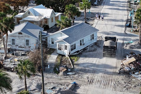 An aerial view of a home sitting on a sand covered road as a dump truck drives by on October 13, 2024 in Manasota Key, Florida