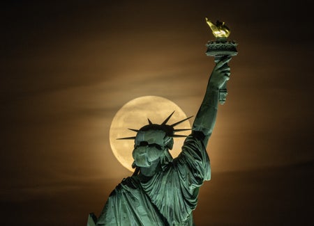 Supermoon rising behind Statue of Liberty