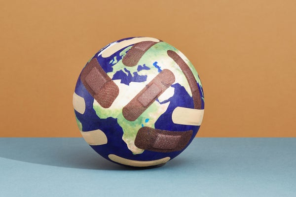 Photo illustration of a globe covered in adhesive bandages sitting on a flat blue colored surface in front of an orange wall