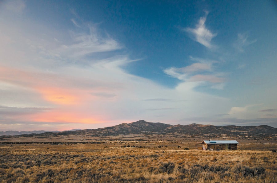 Desert landscape with building on the right and mountain in the background.