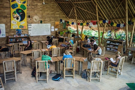 Students sit at bamboo desks while attending class at Green School on May 20, 2013 in Badung, Bali, Indonesia. The classroom is in a building structure is made from bamboo with open sides and a thatched roof