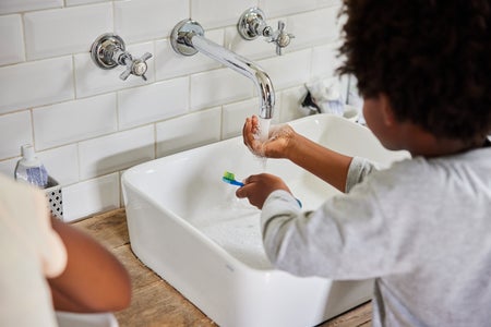 Young siblings brushing their teeth at a bathroom sink