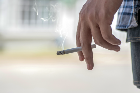 Male hand holding a lit cigarette